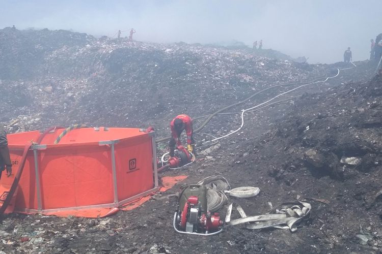 Petugas Damkar Makassar bersama Manggala Agni KLHK saat menyuntikkan flame freeze dengan teknologi nozzle tanam di lokasi kebakaran TPAS Antang, Makassar, Selasa (17/9/2019).