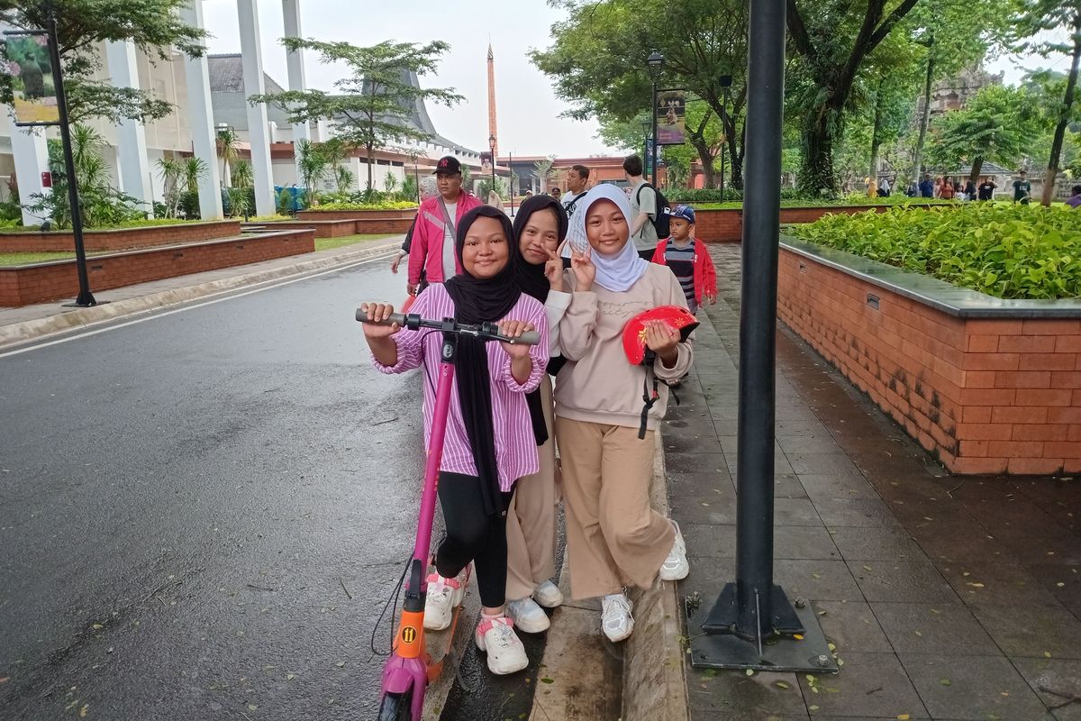 Tiga sekawan asal Pondok Ranggon, Cipayung, Dian (11), Dini (12), dan Lia (12), memilih untuk bermain skuter listrik di tempat wisata Taman Mini Indonesia Indah (TMII), Jakarta Timur, Selasa (18/6/2024).