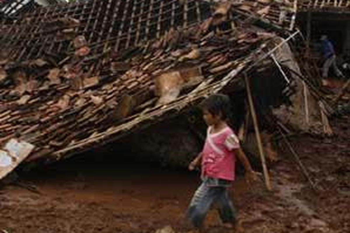 Seorang anak melintas di rumah yang ambruk akibat angin kencang yang melanda Desa Karangsinom, Kecamatan Tirtamulya, Kabupaten Karawang, Jawa Barat, Jumat (25/12/2009).