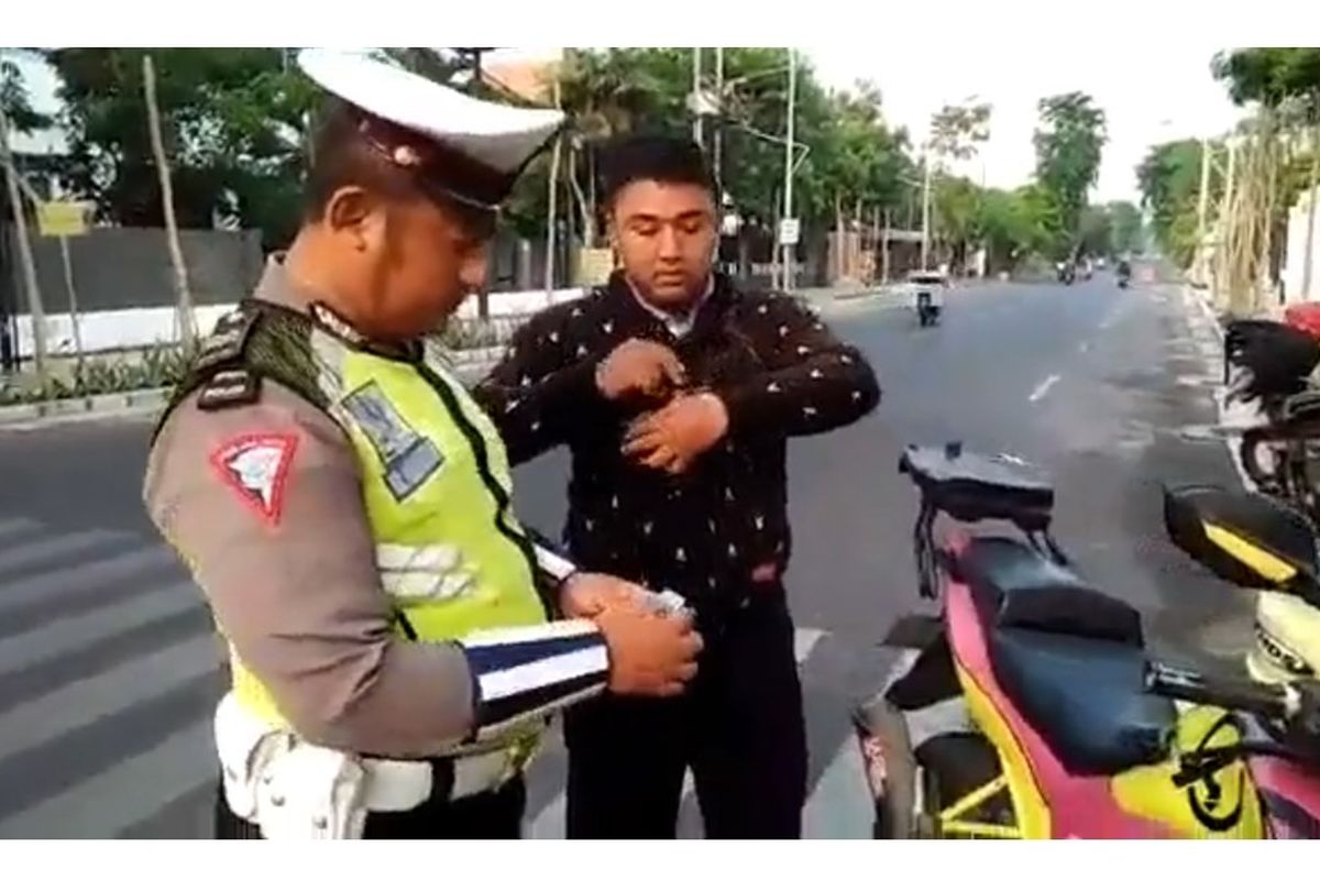 Tangkapan layar dari seorang polisi yang tengah menilang pengawal ambulance.