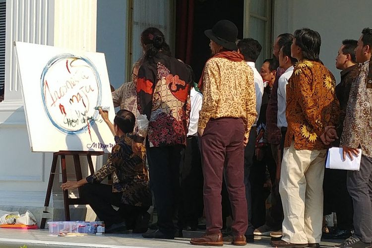 Presiden Joko Widodo melukis Indonesia Maju di sebuah kanvas besar. Para budayawan yang menyaksikan hal itu langsung bertepuk tangan.   Hal itu terjadi saat silaturahmi Jokowi dan para budayawan, di Beranda Istana Merdeka, Jakarta, Jumat (6/4/2018). 