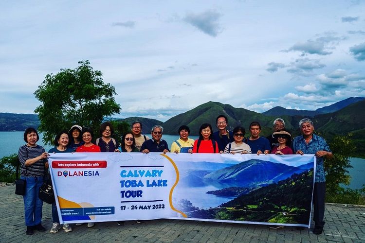 Rombongan turis Singapura berfoto dengan latar belakang keindahan Danau Toba, Jumat (19/5/2023) sore. Belasan turis ini akan plesiran menjelajahi Danau Toba dengan tema Calvary Toba Lake Tour selama seminggu dengan dipandu perusahaan pariwisata Dolanesia.