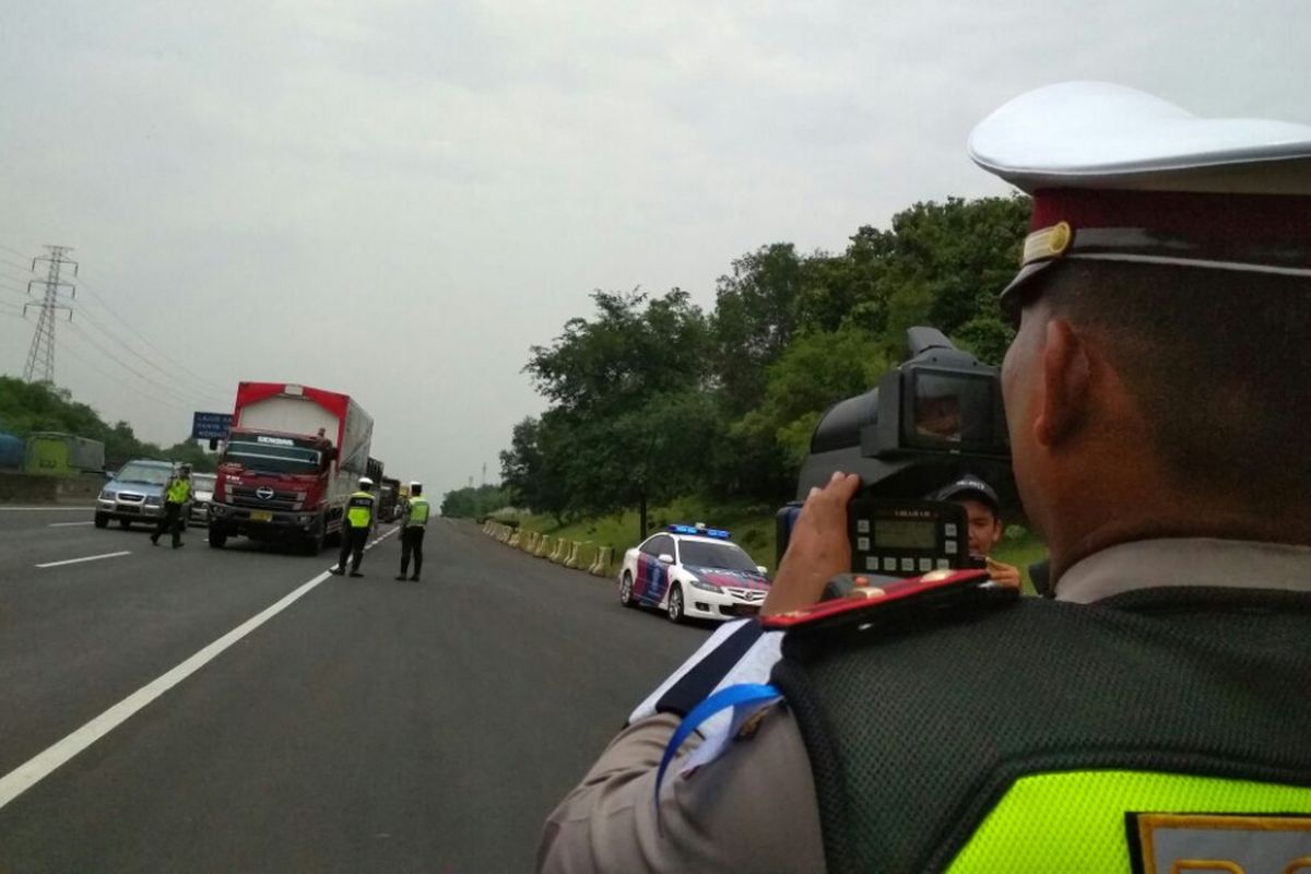 Polisi menggunakan alat speed gun untuk mengukur kecepatan kendaraan di Tol Jakarta-Cikampek dalam penutupan Operasi Zebra Lodaya 2017, Selasa (14/11/2017).