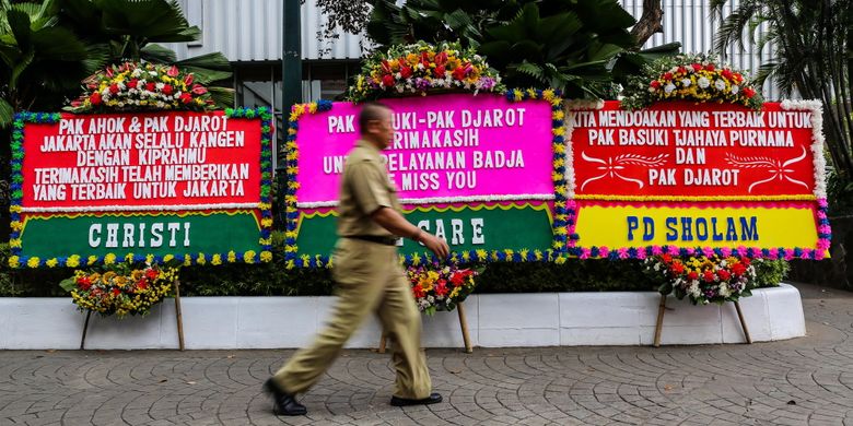 Warga melintas di antara karangan bunga yang ditujukan untuk Basuki Tjahaja Purnama atau Ahok dan Djarot Saiful Hidayat di kompleks Balai Kota DKI Jakarta, Senin (9/10/2017). Karangan bunga tersebut berisi ucapan terima kasih dari warga atas kepemimpinan Basuki dan Djarot selama berpasangan menjadi gubernur dan wakil gubernur DKI Jakarta.