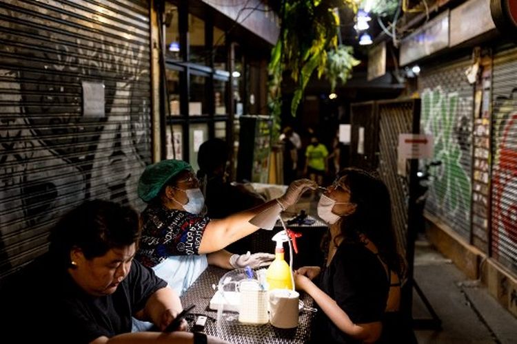 Seorang wanita menjalani tes usap hidung virus corona Covid-19 sebelum diizinkan masuk ke jalur wisata dan kehidupan malam populer Khao San Road di Bangkok pada 10 Desember 2021.