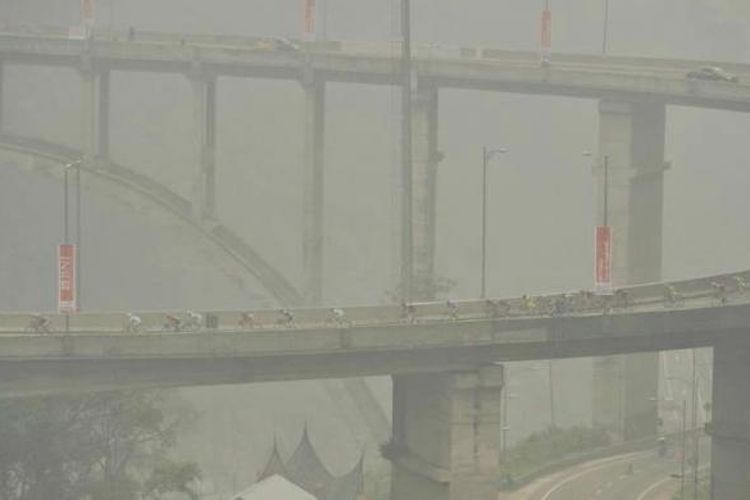 Para pebalap menembus kabut asap saat melintas di Jembatan Kelok Sembilan, Kabupaten Lima Puluh Kota, Sumatera Barat, dalam etape kelima Tour de Singkarak, Rabu (7/10/2015).