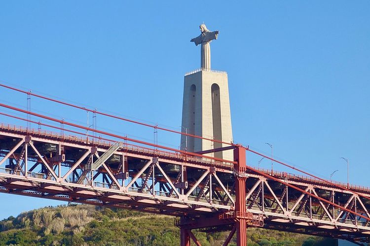 Patung Christ the King atau Cristo Rei di Lisbon, Portugal, yang menghadap ke jembatan.