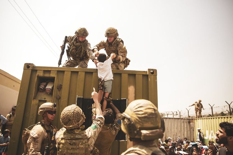 Dalam gambar yang disediakan oleh Korps Marinir AS, pasukan koalisi Inggris dan Turki, bersama dengan Marinir AS, membantu seorang anak selama evakuasi di Bandara Internasional Hamid Karzai di Kabul, Afghanistan, Jumat, 20 Agustus 2021.