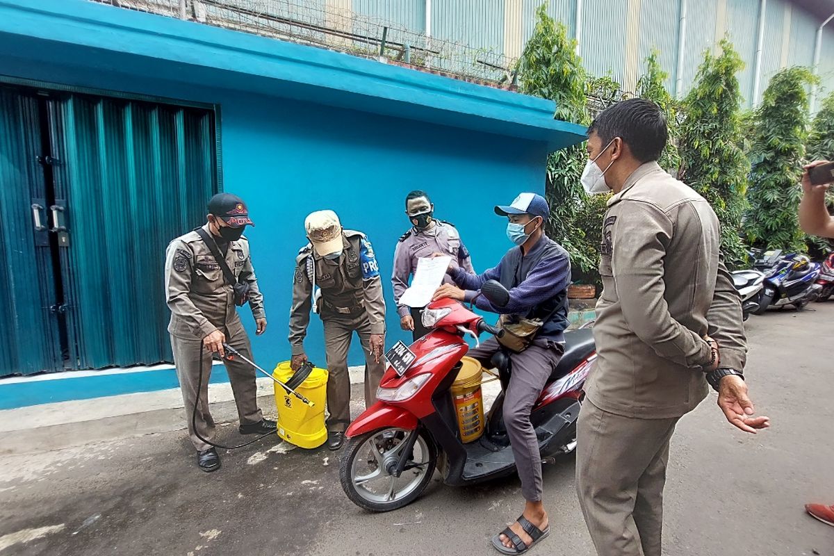 Salah seorang pengendara motor yang hendak memasuki RT01/RW03, Gandasari, Jatiuwung, Kota Tangerang, diminta menunjukkan surat hasil negatif tes antigen kepada petugas yang berjaga, pada Kamis (10/6/2021).