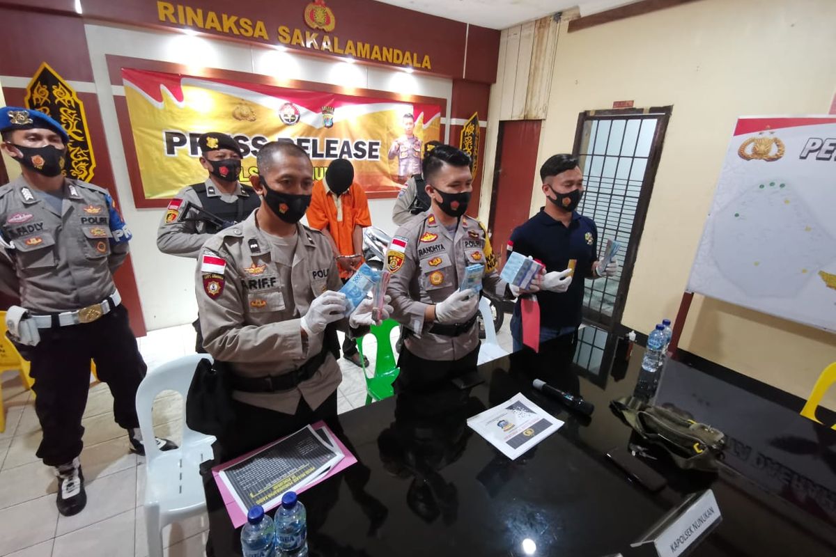 DL (26) security SDIT Ibnu Sina Nunukan (baju orange) dan barang bukti kejahatan dihadirkan dalam prescon di Mapolsek Nunukan Kaltara.Demi judi slot online DL membobol brankas berisi dana BOS Rp160 juta