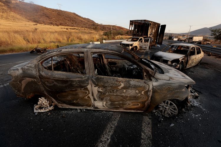 Pemandangan mobil dan truk yang diduga dibakar kelompok kriminal sebagai balasan atas tewasnya bos kartel narkoba Jalisco, Nemesio El Mencho Oseguera, di jalan raya dekat Acatlan de Juarez, Negara Bagian Jalisco, Meksiko, Minggu (22/2/2026).
