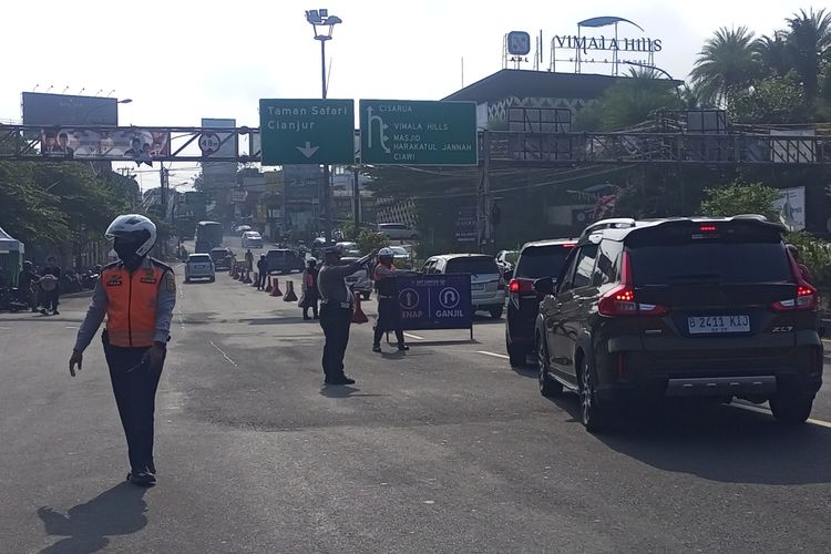 Petugas kepolisian dan Dinas Perhubungan (Dishub) sedang memeriksa pelat nomor kendaraan saat atura ganjil genap diberlakukan di Jalur Puncak Bogor, Jawa Barat, Sabtu (28/9/2024).