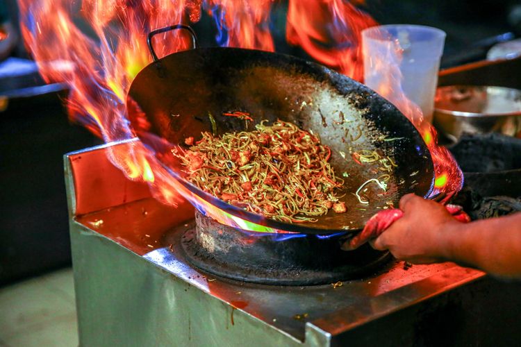 Ilustrasi menumis atau memasak makanan pakai wok. 