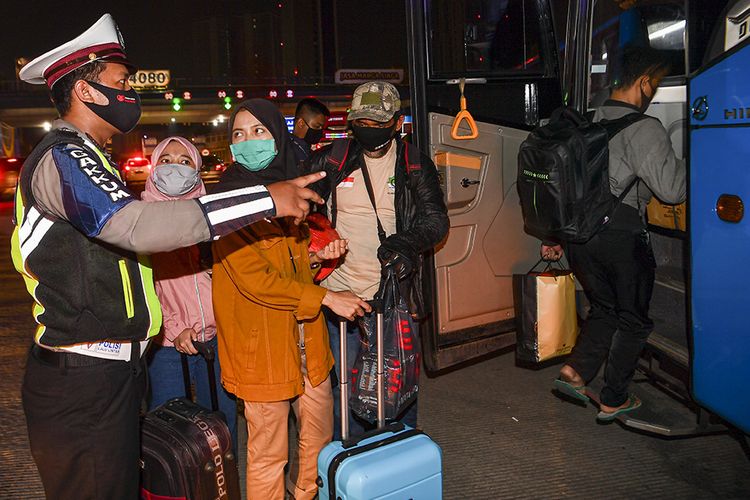 Petugas kepolisian mengarahkan calon pemudik yang terjaring razia penyekatan di Pintu Tol Cikarang Barat, Bekasi, Jawa Barat, untuk menaiki bus yang akan membawa mereka ke Terminal Pulo Gebang, Jakarta, , Kamis (21/5/2020). Calon pemudik yang terjaring razia penyekatan oleh Polda Metro Jaya tersebut dibawa ke Terminal Pulo Gebang untuk kemudian diarahkan kembali menuju Jakarta.