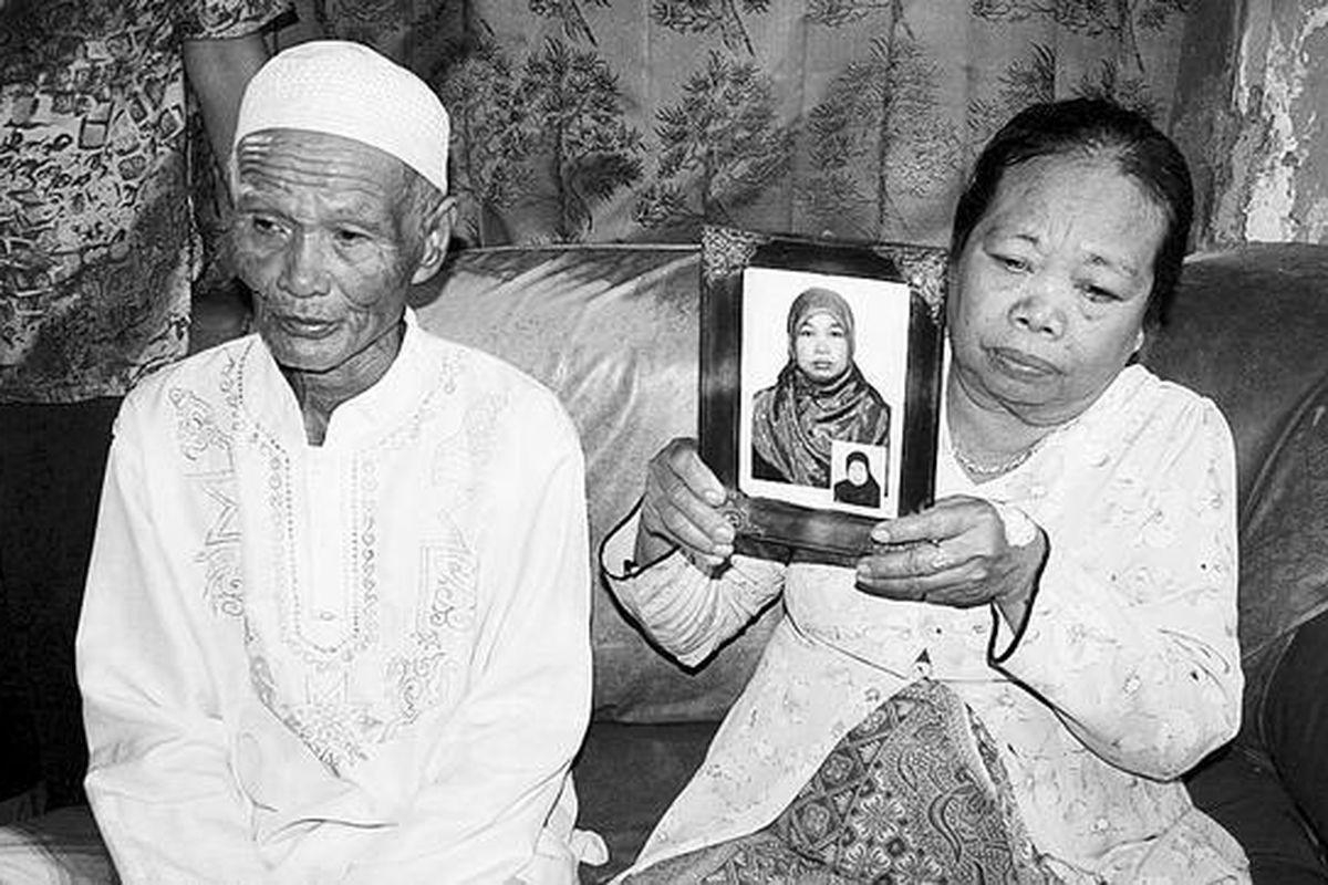 Medi (70) dan Iroh (60), warga Desa Karangjunti, Kecamatan Losari, Kabupaten Brebes, Jawa Tengah, Kamis (13/12), memperlihatkan foto Karni (35), anak mereka yang bekerja sebagai TKI di Arab Saudi. Saat ini, Karni terancam menghadapi hukuman mati karena diduga membunuh anak majikannya yang berusia 4 tahun. 