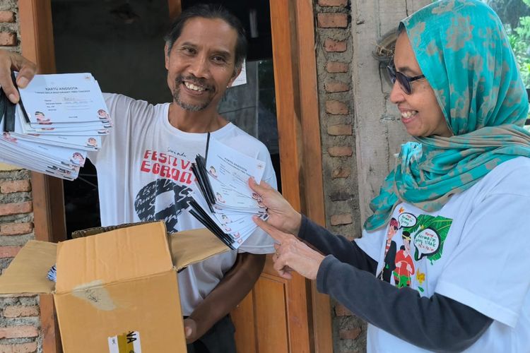 Farha Ciciek dan Supoharjo menunjukkan kartu anggota perpustakaan milik anak-anak di Tanoker Ledokombo, Kabupaten Jember.