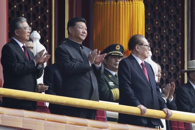 Presiden China Xi Jinping yang mengenakan pakaian Mao Zedong, pendiri China modern, bertepuk tangan di samping mantan Presiden Jiang Zemin dalam perayaan 70 tahun berkuasanya partai komunis di Lapangan Tiananmen pada Selasa, 1 Oktober 2019.