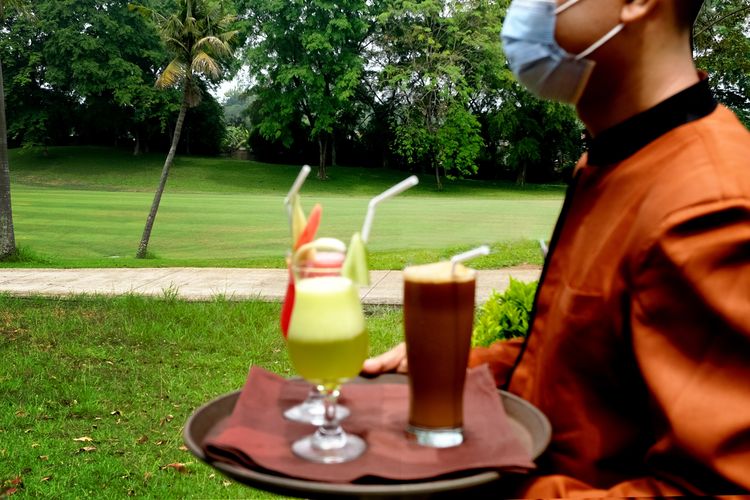 Seorang pramusaji Hotel Puri KIIC sedang mengantarkan minuman untuk pengunjung.