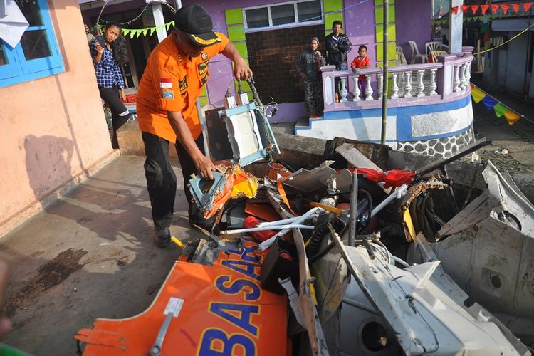 Seorang anggota Basarnas memegang bagian dari bangkai helikopter yang jatuh, di Temanggung, Jawa Tengah, Senin (3/7/2017). Helikopter HR 3602 milik Basarnas yang membawa 4 kru dan 4 regu penyelamat jatuh di Temanggung, Minggu 2 Juli kemarin, menyebabkan semua penumpang tewas.