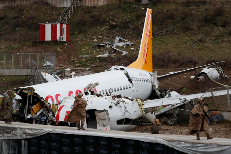Dua prajurit berjaga di depan puing-puing pesawat Pegasus Airlines Boeing 737-86j. Tiga orang tewas setelah pesawat tersebut tergelincir dan terbelah jadi tiga di Bandara Sabiha Gokcen, Istanbul, Turki, pada 5 Februari 2020.