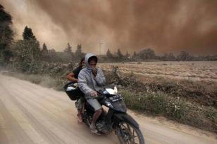 Warga mengendarai sepeda motor meninggalkan desa saat terjadi erupsi Gunung Sinabung di Desa Sukandebi, Karo, Sabtu (13/6/2015). Gunung Sinabung yang kini masih berstatus Awas masih mengalami peningkatan aktivitas.