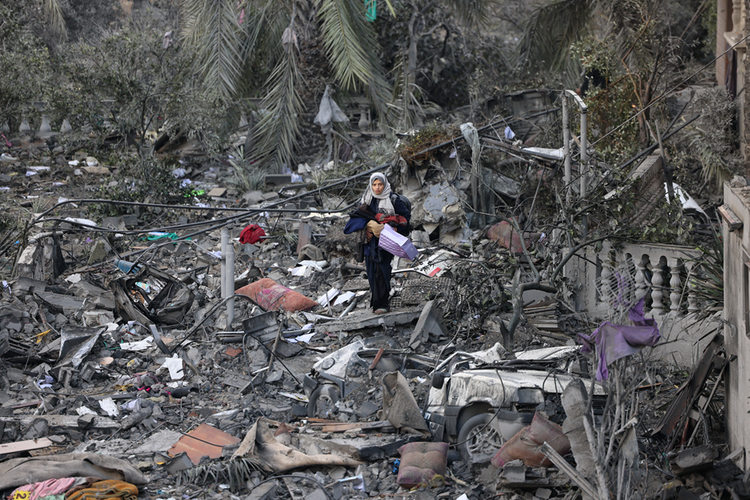 Wanita Palestina berjalan di atas puing-puing bangunan setelah serangan Israel di Rafah, selatan Jalur Gaza, Senin (20/11/2023). 