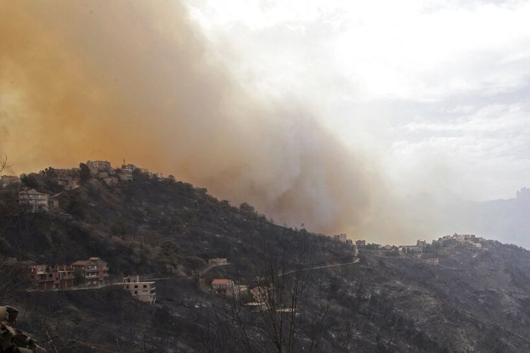 Asap dan kebakaran mengancam sebuah desa dekat Tizi Ouzou sekitar 100 km (62 mil) timur Aljir menyusul kebakaran hutan di wilayah pegunungan ini, Selasa, 10 Agustus 2021. 