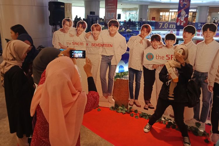 Sejumlah fans grup penyanyi pria asal Korea Selatan, Seventeen, memadati venue acara ulang tahun ketiga The Saem Indonesia di Lotte Shopping Avenue untuk berfoto dengn backdrop idola mereka, Sabtu (14/7/2018).