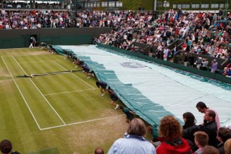 Para petugas lapangan menarik penutup untuk melindungi Court 3 dari hujan yang turun di tengah pertandingan antara Grigor Dimitrov dari Bulgaria dan Grega Zemlja dari Slovenia, pada babak kedua turnamen grand slam Wimbledon, Kamis (27/6/2013).