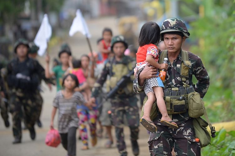 Para prajurit Filipina membantu warga yang meninggalkan kota Marawi, Mindanao akibat baku tembak dengan kelompok militan.