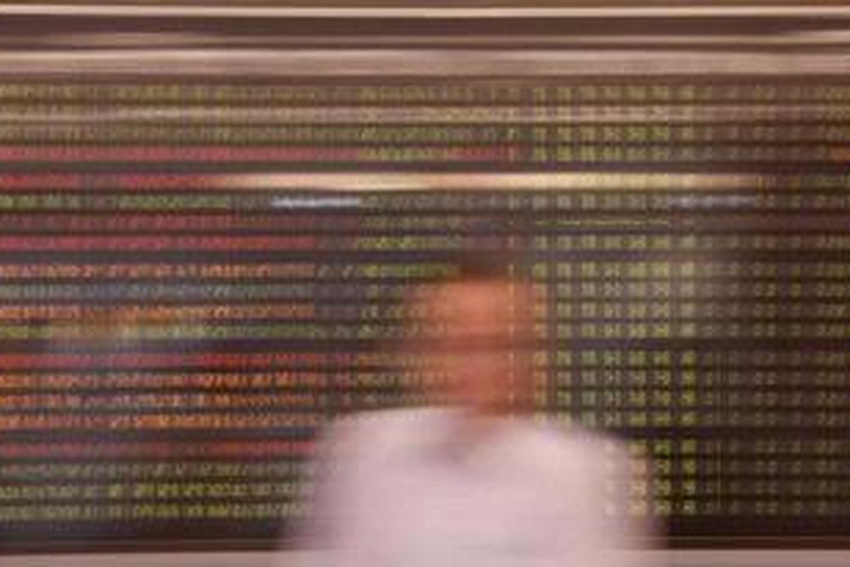 Pengunjung melintas di dekat monitor yang menunjukkan perkembangan indeks harga saham gabungan (IHSG) di Galeri Mandiri Sekuritas di Jakarta, Senin (21/1/2013). 