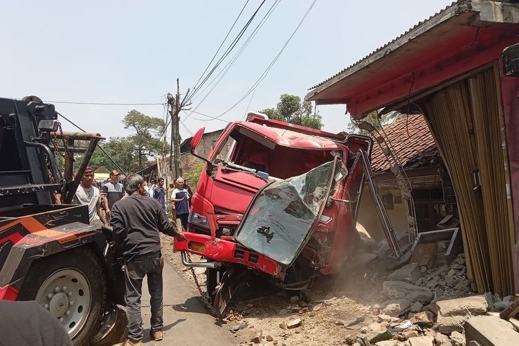 Sejumlah petugas derek berupaya mengevakuasi truk yang rusak akibat menabrak rumah dan bangunan warung di ruas jalan raya Cibeber, Kabupaten Cianjur, Jawa Barat, Senin (13/11/2023). Dalam laka lantas tersebut, seorang pengendara sepeda motor mengalami luka parah.