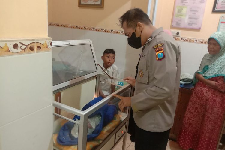 Seorang anggota polisi mengecek bayi berjenis kelamin perempuan yang baru saja ditemukan di teras rumah warga Desa Purwodadi Kecamatan Ringinrejo, Kabupaten Kediri Jawa Timur, Selasa (5/6/2022).