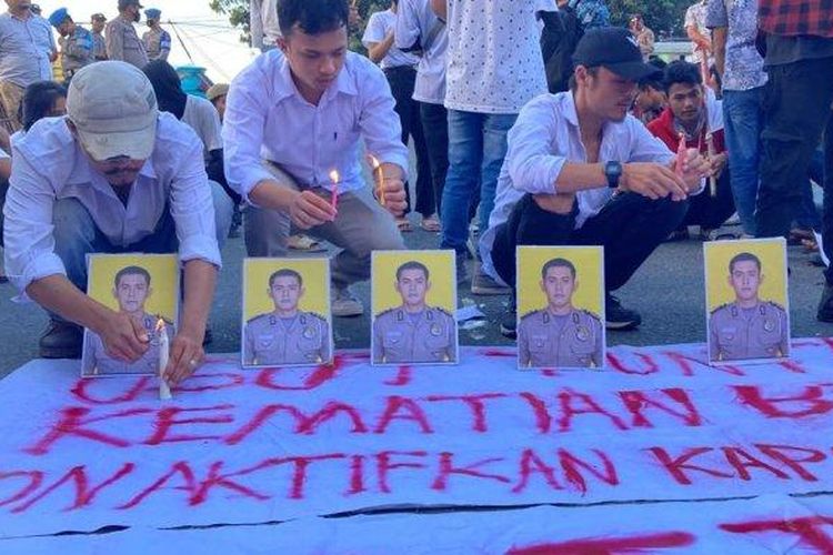 Mahasiswa dari perhimpunan mahasiswa Kabupaten Samosir berunjuk rasa di depan pintu masuk Mapolda Sumut, Rabu (29/3/2023) sore. 
Mereka menyalakan lilin di depan foto almarhum Bripka Arfan Saragih (AS) dan mendesak Polda Sumut mengungkap kasus ini secara transparan 

