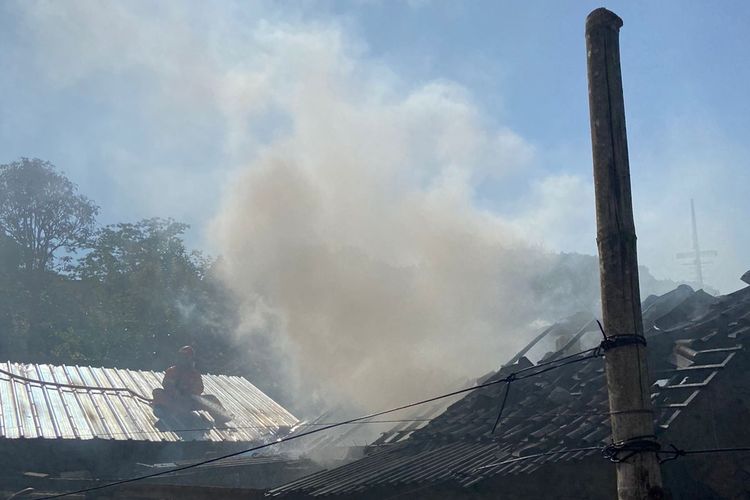 KEBAKARAN: Petugas Damkar Kota Salatiga naik ke atap untuk menyemprotkan air ke rumah yang terbakar, Selasa (25/6/2024) pagi.