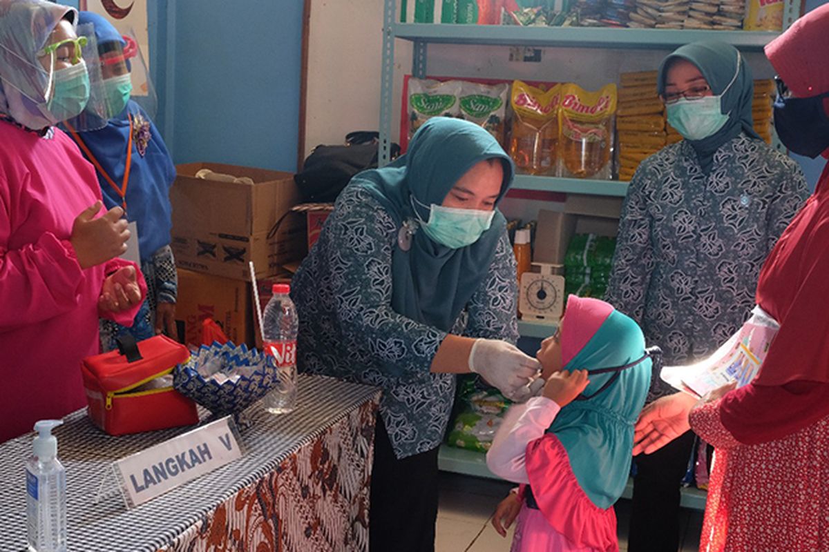 Anak yang sedang di vaksin oleh petugas posyandu dengan protokol kesehatan 