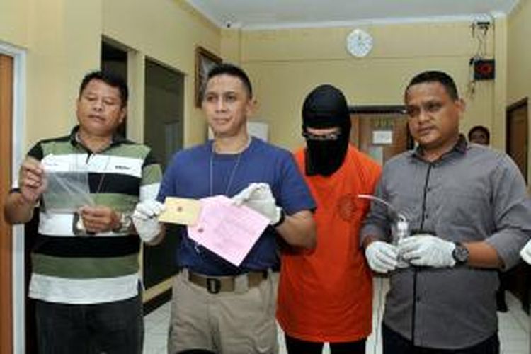 Kasat Narkoba Polres Jakarta Selatan, Hando Wibowo (kedua dari kiri), bersama dua polisi lainnya menunjukkan barang bukti penangkapan Fariz Rustam Munaf atau Fariz RM, di Polres Jakarta Selatan, Selasa (6/1/2015) siang. Hando menghadirkan pula Fariz (mengenakan topeng). Fariz tertangkap tangan menggunakan heroin, ganja, dan sabu, serta menyimpan narkotika tersebut berikut alat isap yang disebut bong, di kediamannya di Perumahan Bintaro Jaya, Tangerang Selatan.