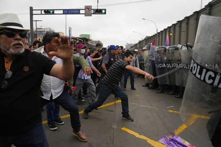 Pendukung mantan Presiden Pedro Castillo menghadapi polisi anti huru hara di sekitar kantor polisi tempat Castillo tiba sebelumnya, di Lima, Peru, Rabu, 7 Desember 2022.