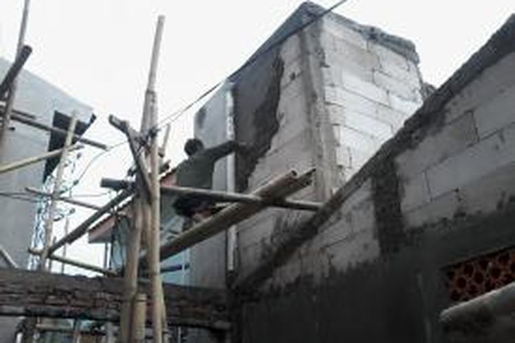 Salah seorang tukang bangunan tengah merampungkan pekerjaan merenovasi rumah di Tanah Tinggi, Jakarta Pusat, Senin (15/7/2013). Tak hanya badan bangunan, para pekerja juga merampungkan instalasi listrik untuk kemudian dipasangi meteran oleh PLN.
