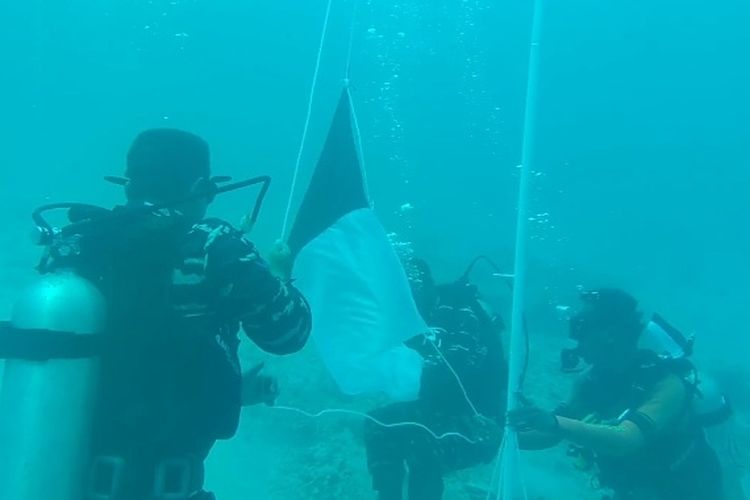 Foto: Prajurit TNI AL Maumere sedang mengibar bendera merah putih di bawah laut tepatnya di perairan Pulau Kojadoi, Rabu (17/8/2022).