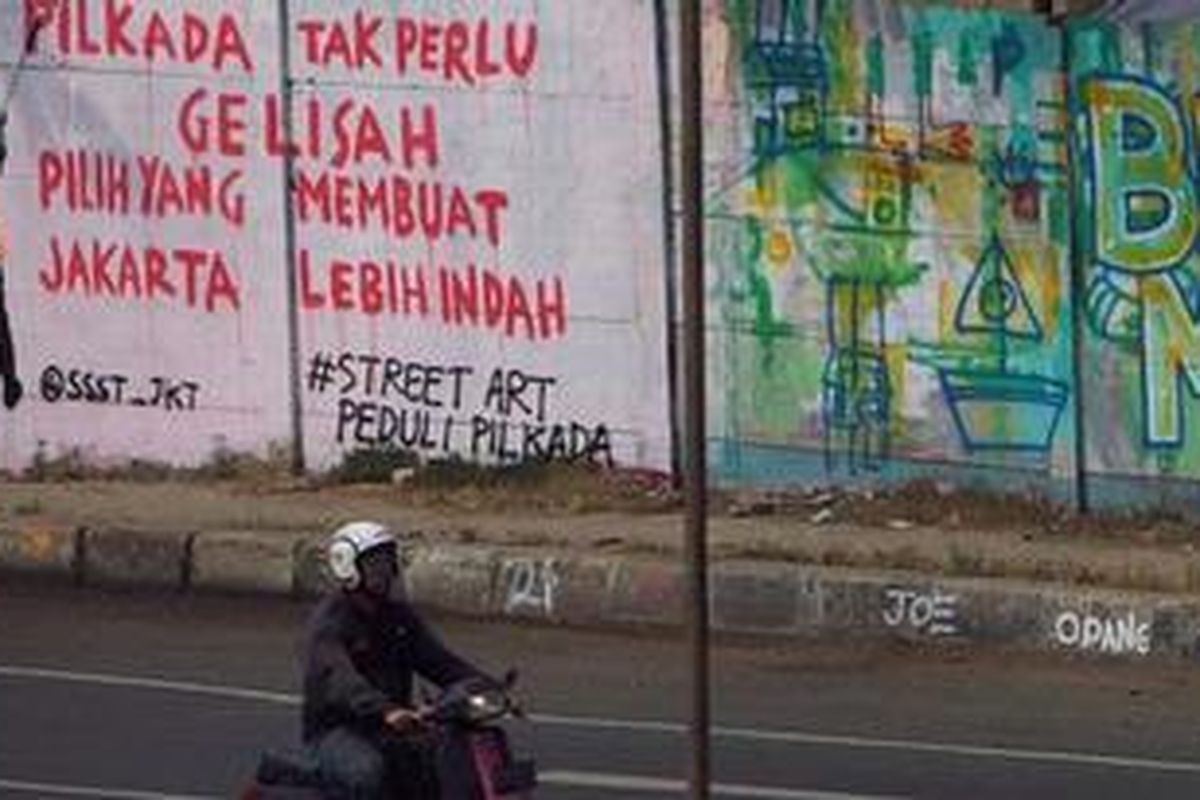 Warga melintas didepan mural yang menghimbau warga tidak perlu gelisan jelang Pilkada DKI putaran kedua di Rawamangun, Jakarta Timur, Sabtu (21/7/2012). Pemilih diharapkan aktif dan kritis dalam memilih kepala daerahnya karena menentukan nasib kota Jakarta selama lima tahun ke depan. 