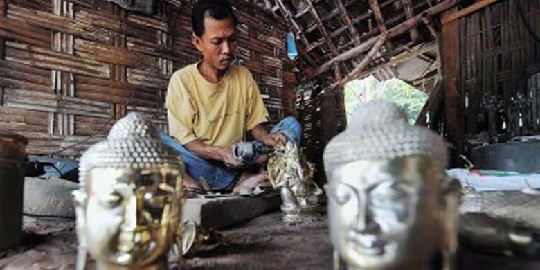 Perajin menyelesaikan pembuatan patung kuningan di sentra industri kecil cor logam di Desa Bejijong, Kecamatan Trowulan, Kabupaten Mojokerto, Jawa Timur, Kamis (18/4/2013).