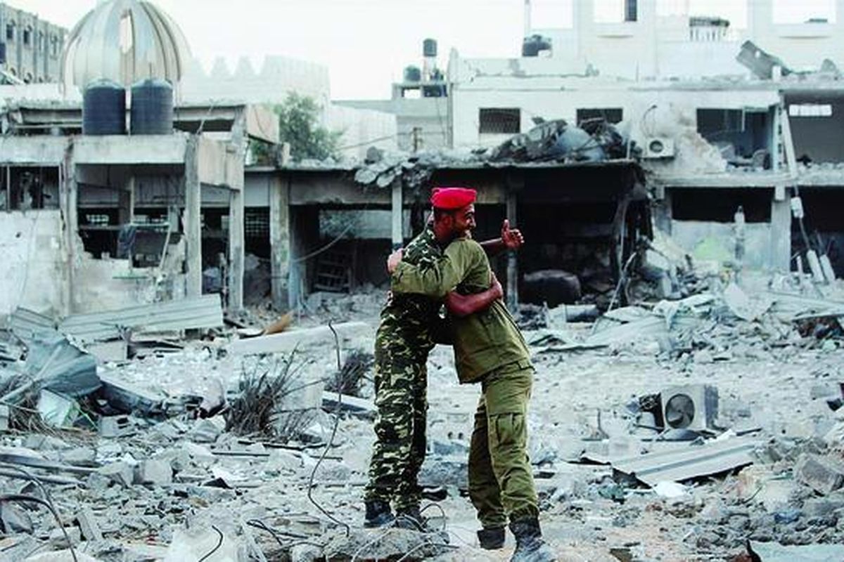 Dua polisi Hamas berpelukan, Kamis (22/11), setelah mereka kembali ke sisa-sisa markas besar mereka di Al-Saraya, Gaza City, yang hancur diserang Israel. Gencatan senjata antara Hamas dan Israel yang difasilitasi Mesir diumumkan sehari sebelumnya setelah pecah pertempuran selama sepekan yang menelan banyak korban jiwa. 