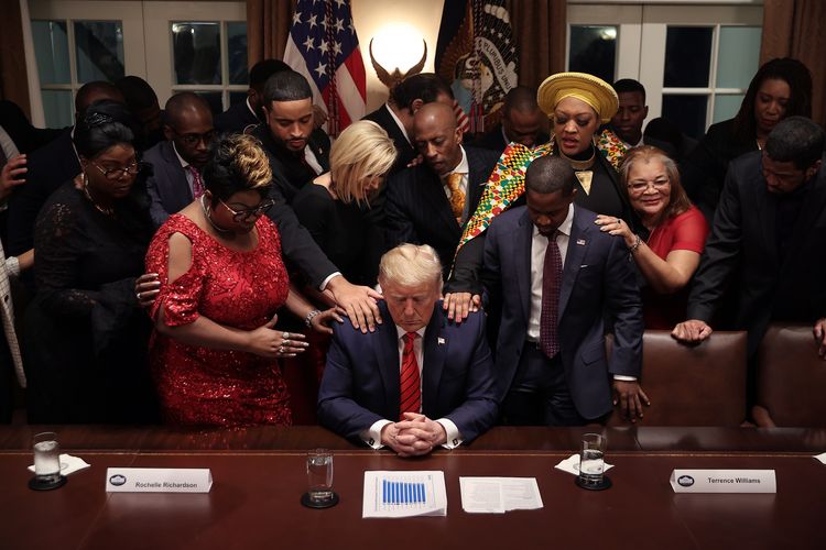 Tokoh Afrika Amerika dan pendukungnya meletakkan tangan di hadapan Presiden Amerika Serikat Donald Trump, di mana mereka mendoakannya dalam pertemuan di Ruang Kabinet Gedung Putih, Washington, pada 27 Februari 2020.