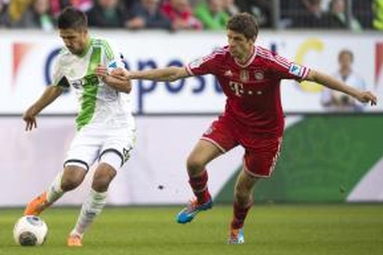 Penyerang Bayern Muenchen Thomas Mueller (kanan) berebut bola dengan penyerang Wolfsburg Vieirinha, pada pertandingan Bundesliga, di Volkswagen Arena, Sabtu (8/3/2014). 