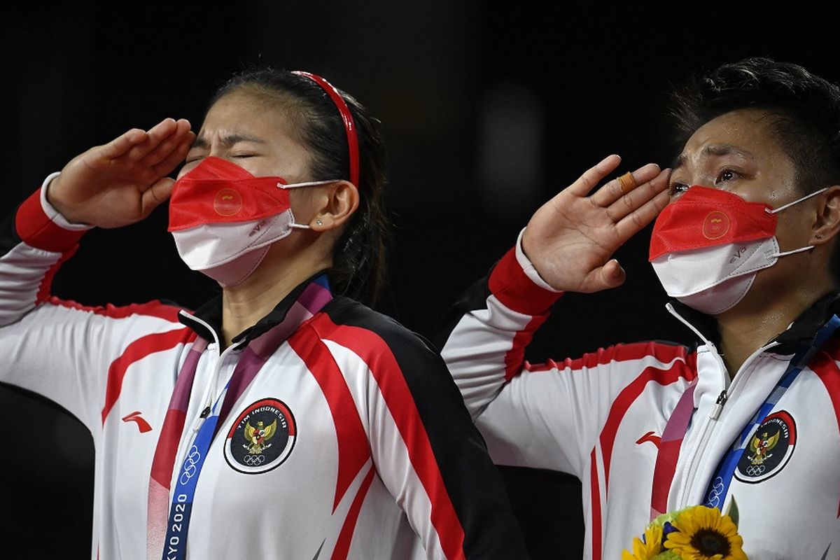 Pasangan ganda putri Indonesia Greysia Polii dan Apriyani Rahayu (kanan) memberi hormat dengan medali emas bulu tangkis ganda putri pada upacara Olimpiade Tokyo 2020 di Musashino Forest Sports Plaza di Tokyo pada 2 Agustus 2021.