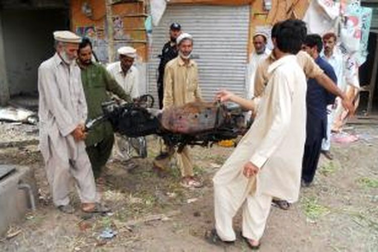 Warga kota Kohat, Pakistan menyingkirkan bangkai sepeda motor pembawa bom yang meledak di dekat sebuah masjid di kota itu. Ledakan bom ini menewaskan dua orang dan melukai belasan orang lainnya.