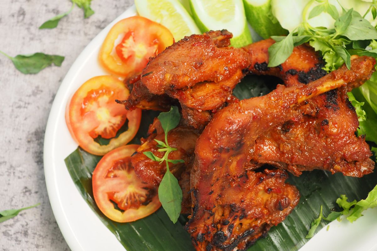 Ayam bakar pedas yang disajikan dengan warna kecokelatan menggoda, beraroma bumbu rempah dan cabai.