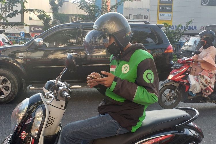 Pengemudi ojol, Satria (20) mengecek aplikasinya setelah membeli kartu jaringan lain, pasca jaringan telkomsel lumpuh total akibat gedung Telkom di Jalan Jenderal Sudirman, Kota Pekanbaru, Riau, terbakar, Selasa (11/8/2020).