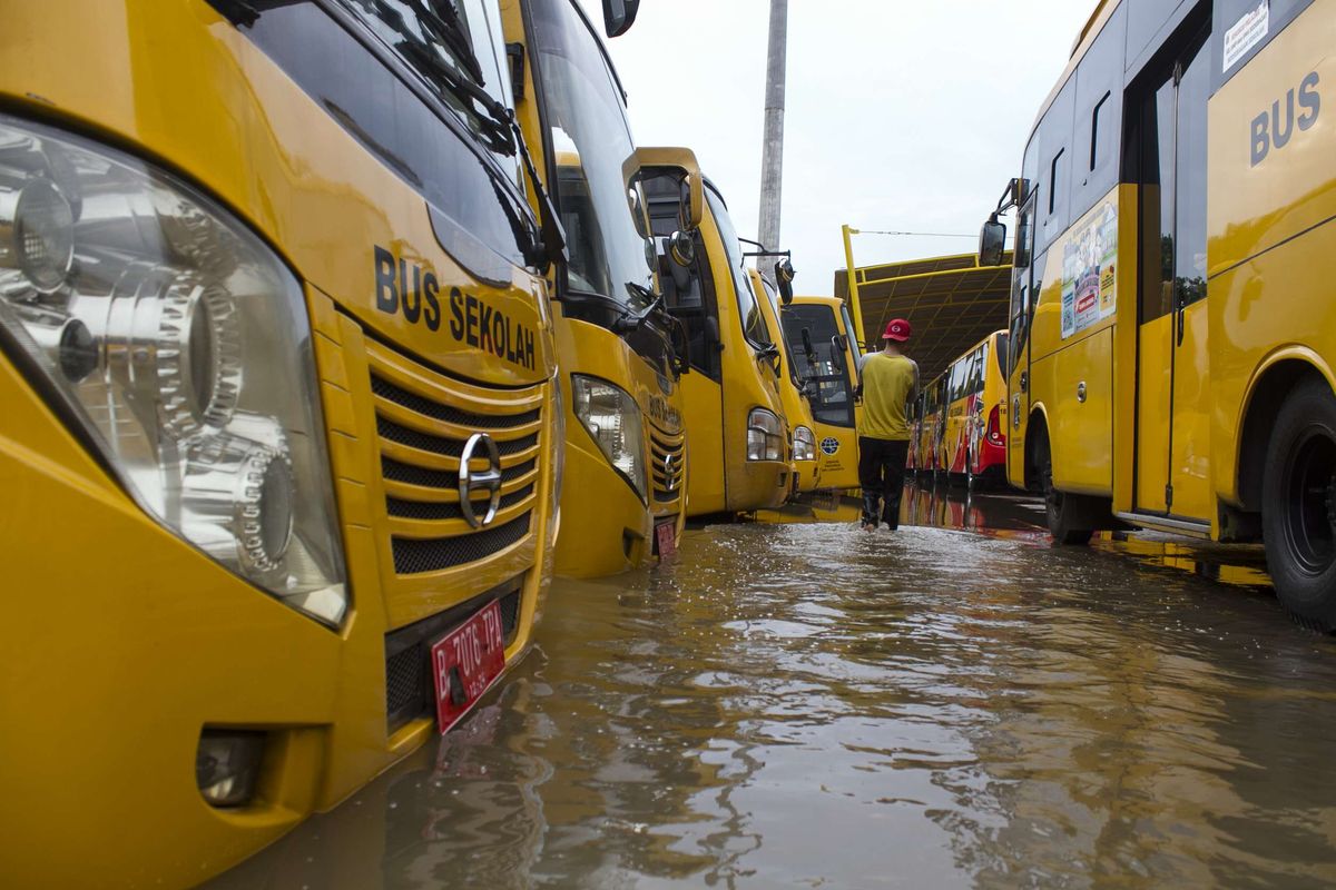 Petugas mengecek bus sekolah yang terendam banjir di Jl. Raya Pondok Gede, Kramat Jati, Jakarta Timur, Rabu (1/1/2020). Luapan air Kali Baru sebabkan wilayah Kramat Jati terendam hingga sebahu orang dewasa.